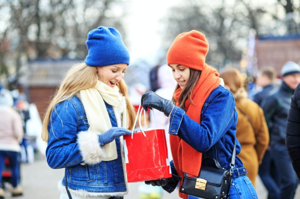 The two sisters met at the Christmas market. Happy people with a gift bag.